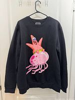 Front view of black Pull & Bear Patrick Star jellyfish sweatshirt on hanger