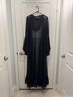 Front view of black sheer cover up hanging on door