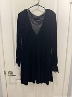 Front view of black velour long-sleeve dress on hanger
