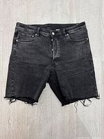 Front view of washed black H&M Bermuda shorts showing frayed hems and overall condition