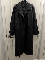 Front view of black faux leather double-breasted trench coat with belt