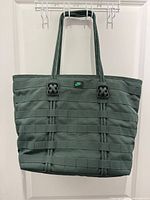 Front view of dark green Nike tote showing webbing design and logo tab