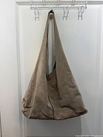 Front view of beige suede shoulder bag showing overall form and strap