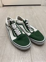 Three-quarter view of both sneakers showing white and green colorway and lightning-bolt detail