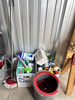 Spin mop bucket, mop and box of cleaners against wall