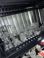 Full view of shelf with multiple crystal pieces including candle holders, vases and dishes