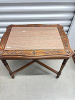 Full view of mahogany accent table showing marble insert, carved border, turned legs and stretcher.