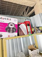 Shelf view showing Instant Pot air fryer lid box, Thermos carafe box, Thermos bottle box, partial salad set box