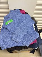 Stack of garments topped with blue marled sweater