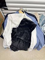 Pile showing white blouse, black velour pants atop light blue jacket
