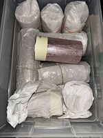Bin containing multiple tissue-wrapped pillar candles, one metallic mauve candle visible