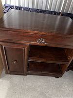 Front view of mahogany TV stand showing door, shelves, carved detail