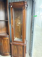 Full view of tall walnut display cabinet with glass door and lower storage