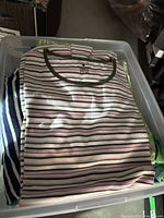 Top view of bin showing pink striped tee and others underneath