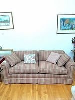 Full front view of striped three-seater sofa with pillows