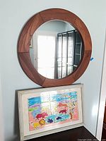 Round wood mirror above framed Sally Huss print