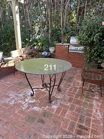Full view of round glass patio table with metal scroll base
