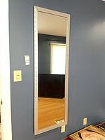 Full view of rectangular wall mirror mounted on blue wall