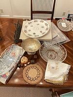All items on table including glass platter box, Seder plate, metal bowls, menorah, linens, trivet and stone fruit