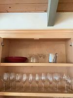 Cabinet shelf with red bowl, two martini glasses and utensil beside