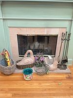 Overall lot in front of fireplace showing tool set, swan planter, baskets, ceramic pot, wire planter, florals, bird figure