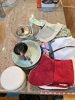 Overview showing ceramic dishes, stainless pitcher, glass lid, linens, white container