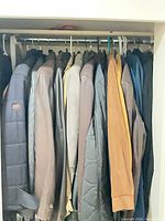 Closet rod with multiple jackets and coats showing variety of colors and materials