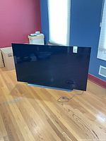 Front view of LG 65-inch OLED TV on stand with power cord visible