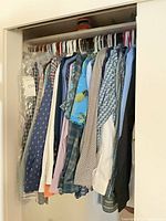 Full closet view showing group of long-sleeve shirts on hangers