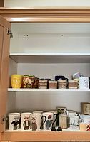 Cabinet showing two shelves of assorted mugs