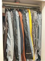 Row of bagged suits hanging in closet