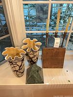 Group view of two visible art glass vases, marble pyramid, wood and metal candle holder