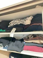 Shelved folded sweaters top and middle shelves showing variety of colors