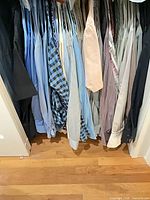 Closet view showing numerous dress shirts of various colours and patterns on hangers