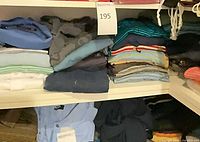 Upper shelf stacks including solid blue, camo, teal shirts and striped polos