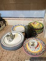 Stack of assorted dinner plates, bowls, mugs showing patterns and quantity