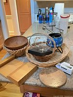 Entire lot on countertop showing baskets, fondue pot, wooden stand, trivet, oximeter boxes