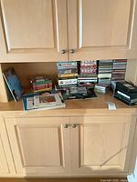 Overview of cabinet shelf showing stacks of VHS tapes, CDs, LaserDisc sleeves and cases