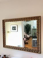Front view of rectangular gold-gilded wall mirror on wall