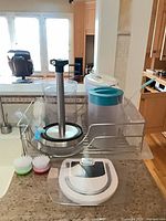 Full lot showing Brita pitcher, cylindrical container, paper towel holder, digital scale, two scrubbers in dish rack