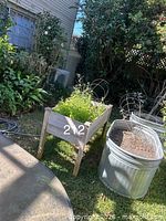 Wooden raised planter on legs beside round galvanized tub with wire supports