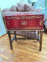 Closed red trunk with gold motif on stand