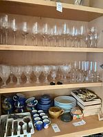Cabinet showing multiple shelves of glassware; middle shelf contains the full set of clear vertical-fluted glasses