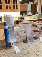 Overview of SodaStream unit, CO2 cylinder, charger box, jars, pitcher, cup and lid on countertop