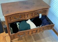 Front view of solid wood dresser with top drawer open showing clothing