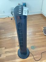 Full view of black tower fan standing on floor with power cord