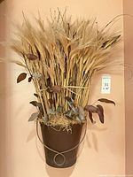 Full view of wall floral arrangement showing metal pocket, grasses and leaves