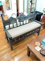 Front angle of carved wood bench with plaid seat