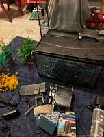 smaller aquarium with hood, blue gravel, plastic plants, larger empty tank behind, accessories scattered