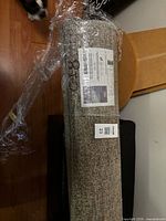 Rolled sealed beige/tan polypropylene area rug